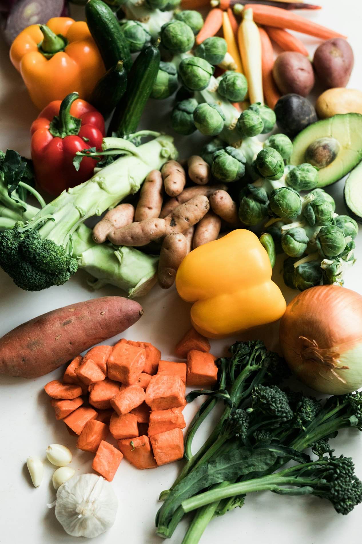 Assorted fresh vegetables arranged on a white surface